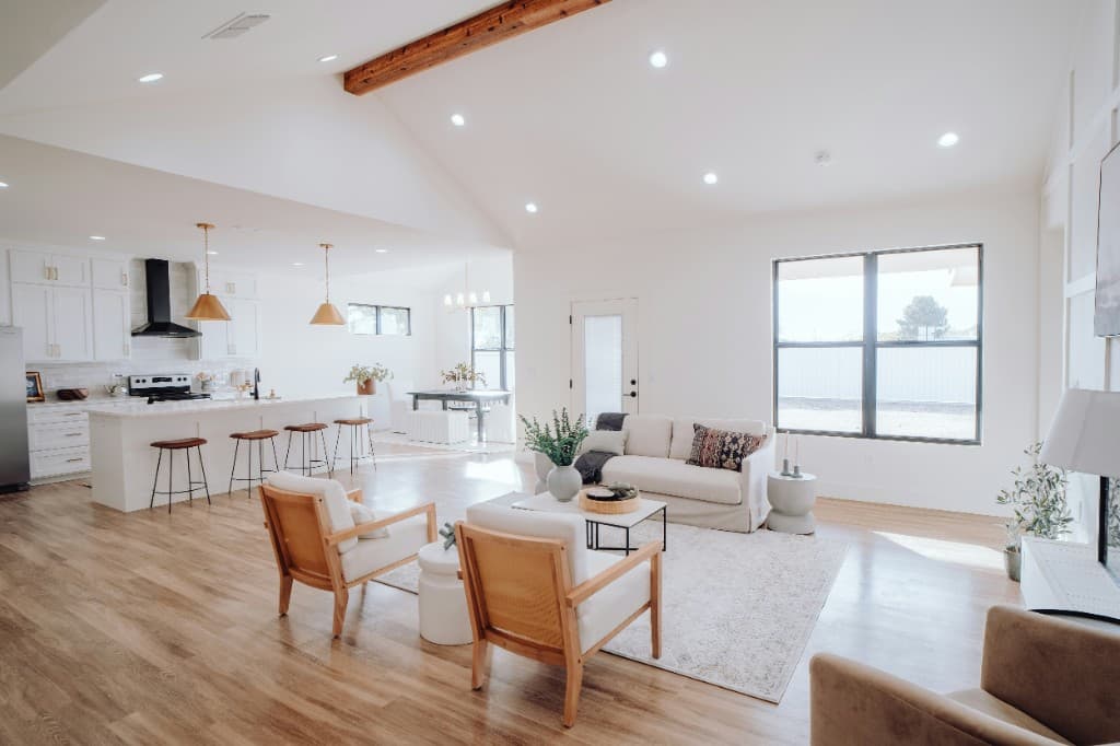 Bright open-plan living room with vaulted ceiling, wood floors, and a modern kitchen